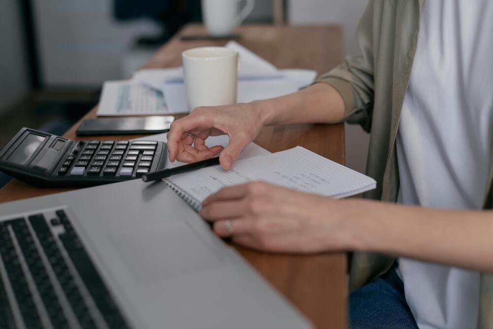 Calculatrice et documents sur une table, illustration du calcul d'un devis architecte en ligne